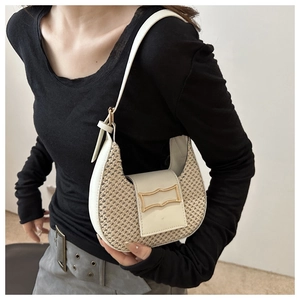 Detail of cream woven hobo bag showing straw texture and gold metal buckle on model