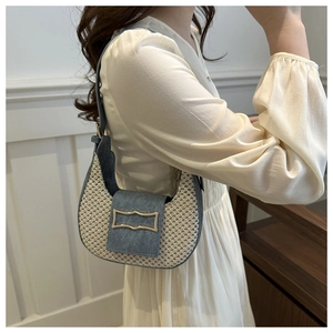 Detail of woven crescent shoulder bag with blue denim patchwork and gold metal buckle