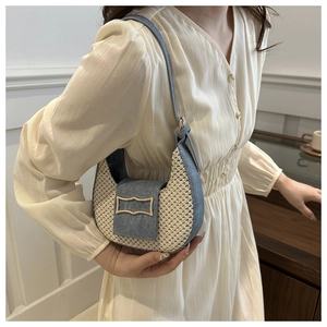 Detail of woven straw and blue denim crescent bag with a gold metal buckle closure