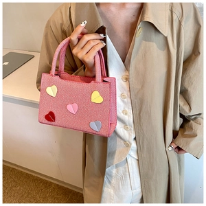 Detailed close-up of a pink mini tote bag with colorful 3D heart charms and woven texture