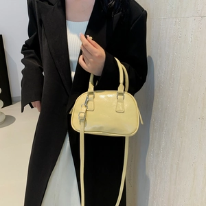Minimalist cream yellow baseball style handbag with glossy finish and slim shoulder strap