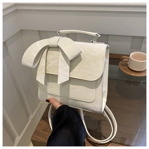 Sac bandoulière beige plissé avec nœud décoratif et bretelles dans un décor lifestyle
