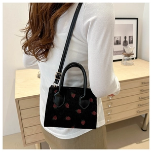 Detail of black corduroy tote with red strawberry embroidery and adjustable strap