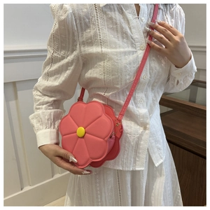 Detailed shot of pink flower shaped crossbody bag with yellow center on white lace top
