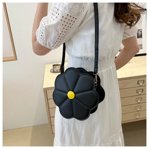Detailed close-up of a black flower-shaped crossbody bag with quilted petals and yellow center