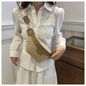 Vintage straw chest bag with brown leather trim and wide strap worn by a female model