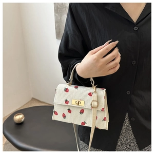 White corduroy crossbody bag with red strawberry print and golden twist lock closure