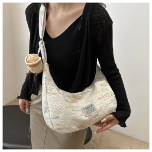 Dettaglio della borsa hobo in tela bianca ricamata con trama trapuntata e ciondolo caffè