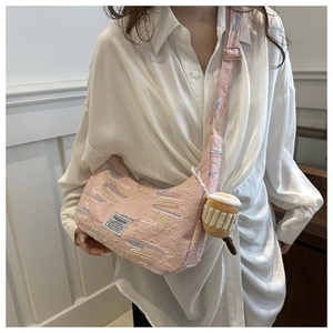 Dettaglio borsa in tela rosa ricamata con ciondolo peluche ed etichetta moda su tracolla