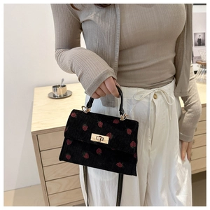 Chic black corduroy Kelly bag featuring red strawberry patterns and gold twist lock closure