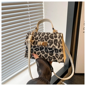 Detail of leopard print mini handbag featuring golden twist lock and adjustable shoulder strap