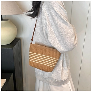 Détail du sac seau en paille tissée avec rayures blanches et fine bandoulière brune