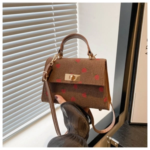 Detail of brown corduroy bag with strawberry pattern and golden metallic twist lock