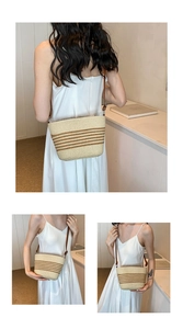 Detail of woven straw crossbody bag featuring natural beige texture and brown stripes