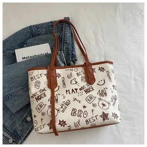 Dettaglio della borsa tote in pelle PU con stampe graffiti e manici marroni su sfondo