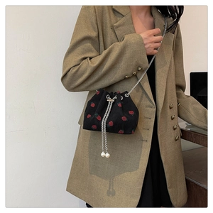 Detail of black corduroy bucket bag with strawberry embroidery and pearl drawstring charms