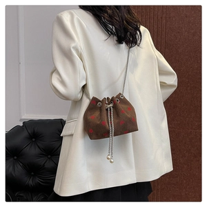 Detail of brown corduroy bucket bag with strawberry embroidery and pearl chain