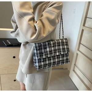 Model wearing a black and white checkered plaid tote bag with bow embroidery detail