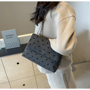 Detailed view of dark grey polka dot crossbody bag with delicate bow embroidery and chain strap