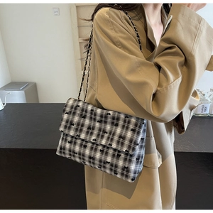 Detail of plaid crossbody bag with bow motif paired with a classic camel trench coat
