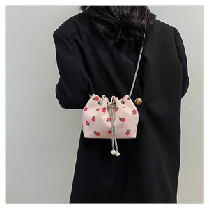 Detail of pink corduroy bucket bag with strawberry print and elegant pearl drawstring