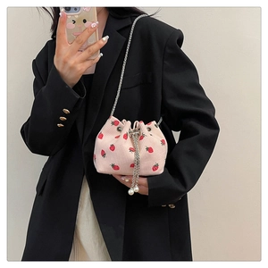 Detail of pink corduroy bucket bag with strawberry print and pearl drawstring