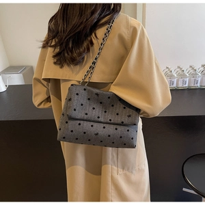 Detail of grey plaid tweed crossbody bag with bow accents on a trench coat