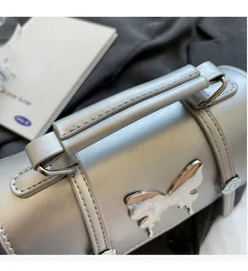 Gros plan du sac à main en cuir argenté avec un ornement papillon métallique chic