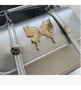 Détail d'un sac à main argenté métallisé avec boucle papillon liquide et coutures droites