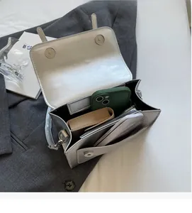 Vue intérieure du sac bandoulière argenté montrant le compartiment principal et la pochette