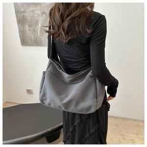 Detailed view of the large capacity canvas tote bag worn over the shoulder by a model