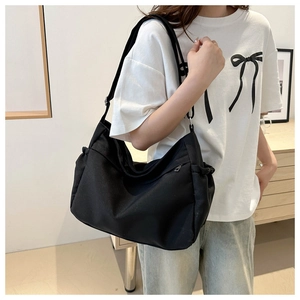 Detail of a large black canvas bucket bag featuring a functional side zipper pocket