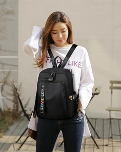 Detail eines schwarzen Nylon-Rucksacks mit buntem LOVE-Gurtband und Reißverschluss