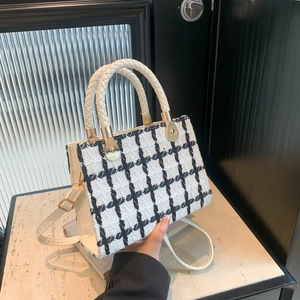 Classic black and white houndstooth tweed handbag with woven handles and golden hardware