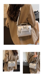 Détail du sac à bandoulière argenté avec boucle papillon sur une veste marron chic