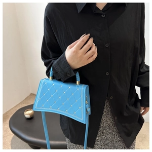 Borsa a tracolla blu trapuntata con borchie dorate e manico intrecciato sul modello