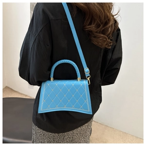 Dettaglio della borsa a tracolla trapuntata blu con borchie a cuore e base curva