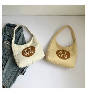 Close-up of cream and yellow canvas tote bags with brown leather logo patches on grey background