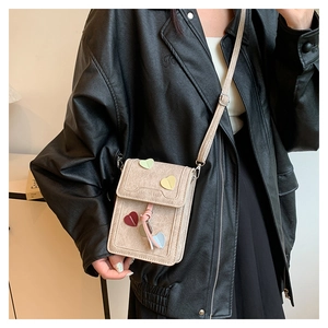 Detail of beige crossbody phone bag with colorful heart patches and fashion bag engraving