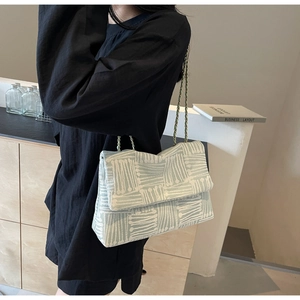 Detail of mint green woven tote bag with metallic chain strap and textured geometric pattern