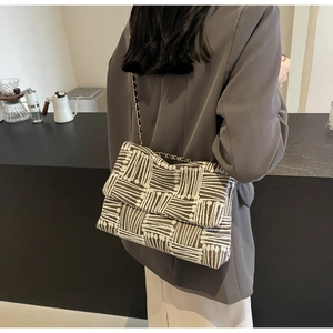 Detail of vintage geometric textured crossbody bag with gold chain strap on model