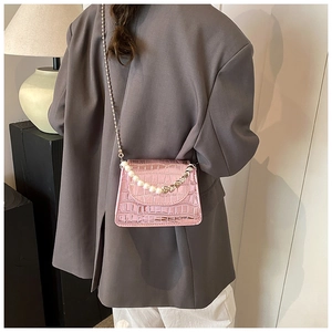 Détail du mini sac rose fuchsia à motif croco avec anse en perles et breloques en cœur