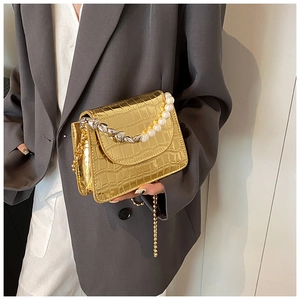 Détail du petit sac doré à motif crocodile avec poignée en perles et chaîne