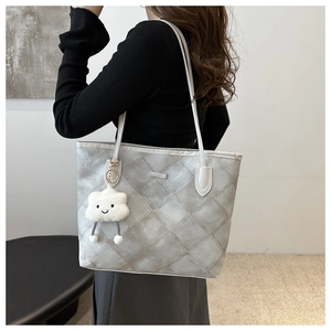 Gray quilted tote bag with double straps and cloud plush charm shown on model