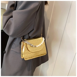 Détail du mini sac doré brillant à motif crocodile avec poignée en perles et chaîne