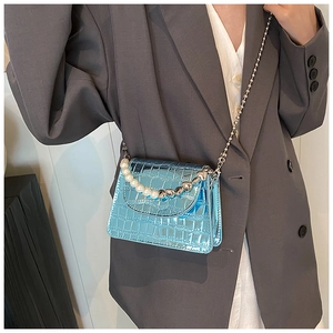 Détail du mini sac bleu à motif crocodile avec poignée en perles et chaîne argentée