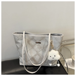 Détail d'un sac cabas gris matelassé avec motif à losanges et breloque nuage