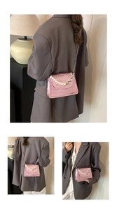Détail d'un petit sac bandoulière rose effet crocodile avec anse en perles et chaîne