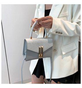 Close-up of glitter flap and gold metal lock on grey crossbody sequin handbag