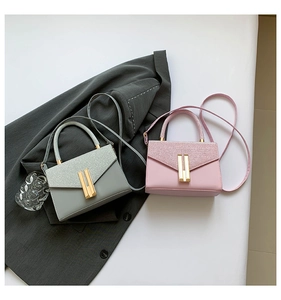 Detail of glitter flap texture and gold metal bar lock on pink and green crossbody bags